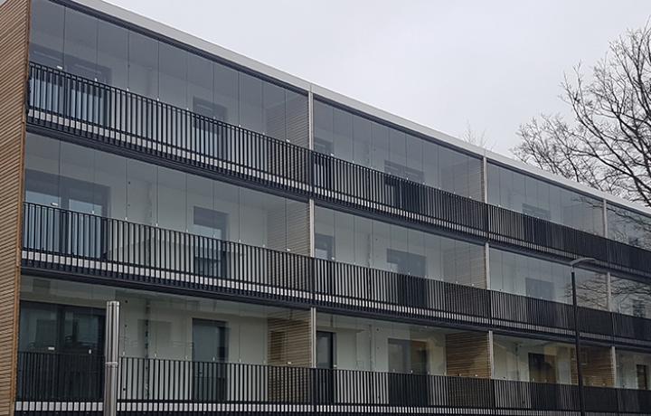 Geschosshohe Lumon Balkonverglasungen montiert hinter einem Stabgeländer, Beispiel Neubau-Objekt Geretsried